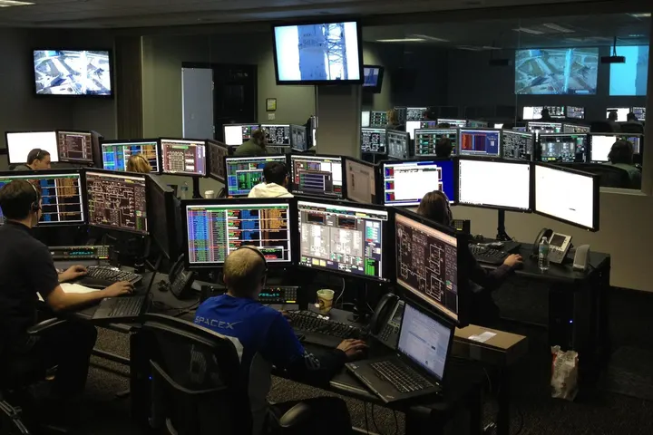 Operators seen from behind at a bank of screens in an operations room