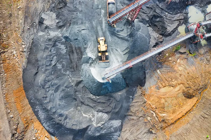 Aerial view of a loader, conveyors and ore stockpiles at a mine
